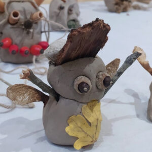 Figura de fang antropomòrfica amb ulls que són aglans, braços que són branques, fulles que són ales i una gorra feta amb una pedra i un tros de fusta.